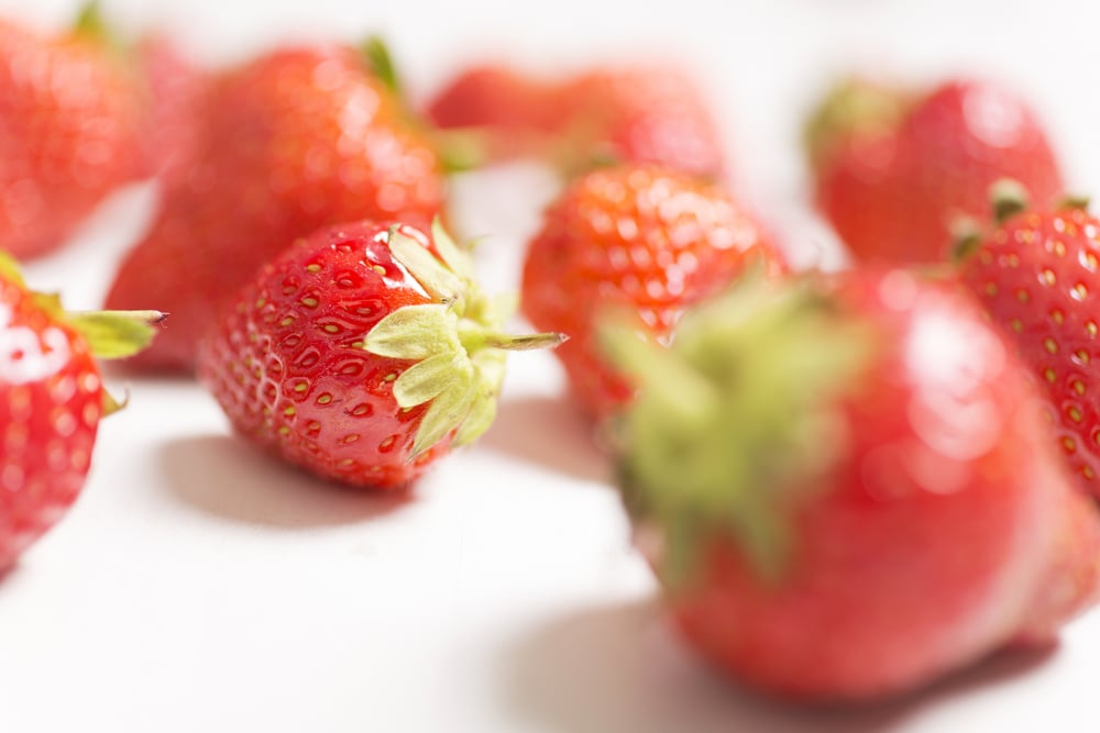 Fresh red strawberries on a light wooden kitchen work surface