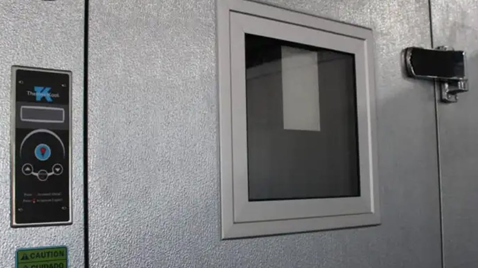 Thermo-Kool walk-in door with a viewing window, beside a wall-mounted Thermo-Kool monitoring and alarm panel