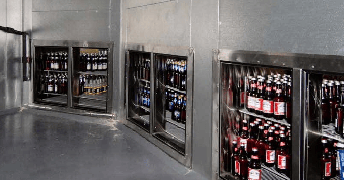 Custom cooler with top all metal. At the bottom of each section are dual glass doors showing the coolers filled with bottled beer.